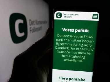 Stuttgart, Almanya - 07-11-2025: Danimarka partisi Detektif Konservatif Folkeparti 'nin (KF) internet sayfası logonun önünde bulunan kişi. Telefon ekranının merkezine odaklan.