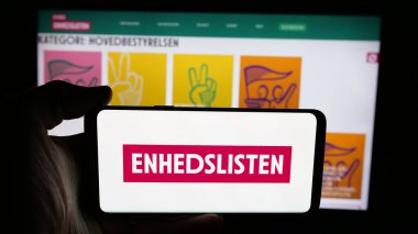 Stuttgart, Almanya - 07-11-2025: Danimarka partisi Enhedslisten logosu olan cep telefonu sahibi kişi - De Rod-Gronne EL web sayfasının önünde ekranda. Telefon ekranına odaklan.
