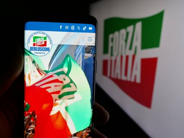 Stuttgart, Almanya - 07-17-2025: İtalyan siyasi partisi Forza Italia 'nın (FI) web sayfası logonun önünde duran kişi. Telefon ekranının merkezine odaklan.