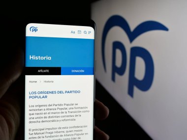 Stuttgart, Almanya - 07-17-2025: İspanyol siyasi partisi Partido Popular 'ın (PP) web sayfası logo önünde bulunan kişi. Telefon ekranının merkezine odaklan.