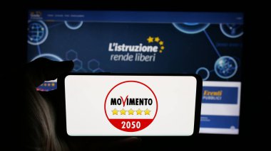 Stuttgart, Almanya - 07-17-2025: İnternet sayfası önünde üzerinde İtalyan partisi Movimento 5 Stelle (M5S) logosu bulunan kişi. Telefon ekranına odaklan.