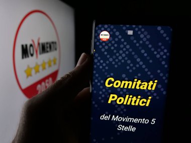 Stuttgart, Almanya - 07-17-2025: İtalyan partisi Movimento 5 Stelle 'nin (M5S) web sayfası logonun önünde duran kişi. Telefon ekranının merkezine odaklan.