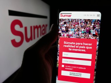 Stuttgart, Almanya - 07-18-2025: İspanyol siyasi partisi Movimiento Sumar 'ın web sayfası logonun önünde duran kişi. Telefon ekranının merkezine odaklan.