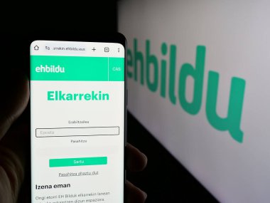 Stuttgart, Almanya - 07-18-2025: İspanyol partisi Euskal Herria Bildu 'nun (EHBildu) internet sayfası logonun önünde bulunan kişi. Telefon ekranının merkezine odaklan.