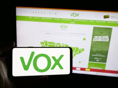 Stuttgart, Almanya - 07-18-2025: İnternet sitesi önünde Vox adlı İspanyol siyasi partisinin logosunu elinde tutan kişi. Telefon ekranına odaklan.