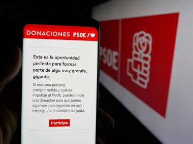 Stuttgart, Almanya - 07-18-2025: Partido Socialista Obrero Espanol 'un (PSOE) web sayfası logonun önünde bulunan kişi. Telefon ekranının merkezine odaklan.
