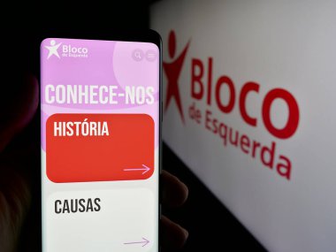 Stuttgart, Almanya - 07-18-2025: Portekizli parti Bloco de Esquerda 'nın (BE) web sayfası logonun önünde cep telefonu tutan kişi. Telefon ekranının merkezine odaklan.