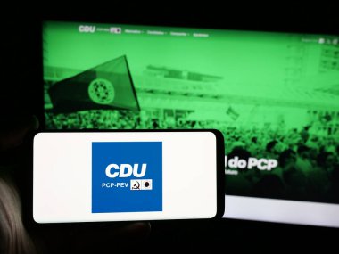 Stuttgart, Almanya - 07-18-2025: İnternet sitesi önünde üzerinde Coligacao Democratica Unitaria (CDU PCP-PEV) logosu olan akıllı telefon sahibi kişi. Telefon ekranına odaklan.