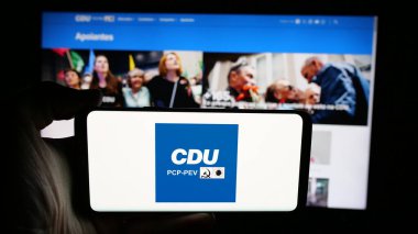 Stuttgart, Almanya - 07-18-2025: İnternet sayfası önünde Coligacao Democratica Unitaria (CDU PCP-PEV) logosu olan kişi. Telefon ekranına odaklan.