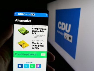 Stuttgart, Almanya - 07-18-2025: Coligacao Democratica Unitaria 'nın (CDU PCP-PEV) web sayfası logonun önünde duran kişi. Telefon ekranının merkezine odaklan.