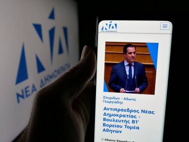 Stuttgart, Almanya - 07-18-2025: Yunan siyasi partisi Nea Dimokratia 'nın (ND) web sayfası logo önünde bulunan kişi. Telefon ekranının merkezine odaklan.