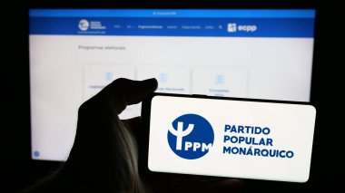 Stuttgart, Almanya - 07-18-2025: Partili Partili Popüler Monarquico (PPM) logosu olan cep telefonu web sayfası önünde ekranda. Telefon ekranına odaklan.