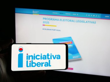 Stuttgart, Almanya - 07-18-2025: İnternet sitesi önünde üzerinde Portekiz partisi Iniciativa Liberal 'in (IL) logosu bulunan akıllı telefon sahibi kişi. Telefon ekranına odaklan.