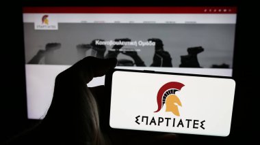 Stuttgart, Almanya - 07-21-2025: Yunan siyasi partisi Spartiates 'in logosunun bulunduğu cep telefonu web sayfası önünde ekranda. Telefon ekranına odaklan.
