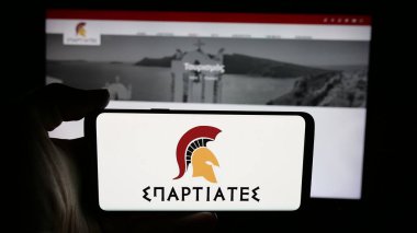 Stuttgart, Almanya - 07-21-2025: Yunan siyasi partisinin Spartiates logosunun bulunduğu cep telefonu web sayfası önünde ekranda. Telefon ekranına odaklan.