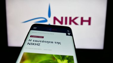 Stuttgart, Almanya - 07-21-2025: Logonun önünde Dimokratiko Patriotiko Kinima (NIKI) partisinin web sitesi bulunan cep telefonu. Telefon ekranının sol üst kısmına odaklan.