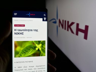 Stuttgart, Almanya - 07-21-2025: Logonun önünde Dimokratiko Patriotiko Kinima (NIKI) partisinin web sayfası ile akıllı telefon tutan kişi. Telefon ekranının merkezine odaklan.