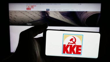 Stuttgart, Almanya - 07-21-2025: Yunan partisi Kommounistiko Komma Elladas 'ın (KKE) logosunun bulunduğu cep telefonu web sayfası önünde duruyor. Telefon ekranına odaklan.