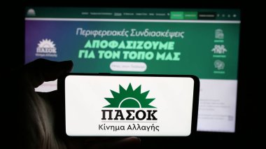 Stuttgart, Almanya - 07-21-2025: Parti logosu olan cep telefonu sahibi Panellinio Sosialistiko Kinima (PASOK) web sayfası önünde ekranda. Telefon ekranına odaklan.