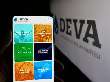 Stuttgart, Almanya - 07-23-2025: Parti Demokrasi ve Atilim Partisi 'nin (DEVA) web sayfası logonun önünde duran kişi. Telefon ekranının merkezine odaklan.