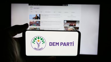 Stuttgart, Almanya - 07-23-2025: İnternet sayfası önünde Halklarin Esitlik ve Demokrasi Partisi 'nin (DEM) logosuna sahip cep telefonu sahibi kişi. Telefon ekranına odaklan.