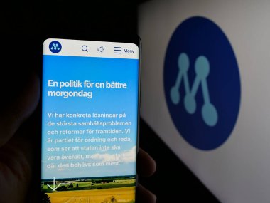 Stuttgart, Almanya - 07-24-2025: Partili Moderata Samlingspartiet 'in (Moderaterna) web sayfası logonun önünde bulunan kişi. Telefon ekranının merkezine odaklan.