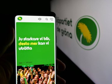 Stuttgart, Almanya - 07-24-2025: İsveç partisi Miljopartiet de Grna 'nın (MP) internet sayfası logo önünde bulunan kişi. Telefon ekranının merkezine odaklan.