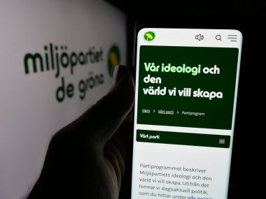 Stuttgart, Almanya - 07-24-2025: İsveç partisi Miljopartiet de Grona 'nın (MP) internet sayfası logo önünde bulunan kişi. Telefon ekranının merkezine odaklan.
