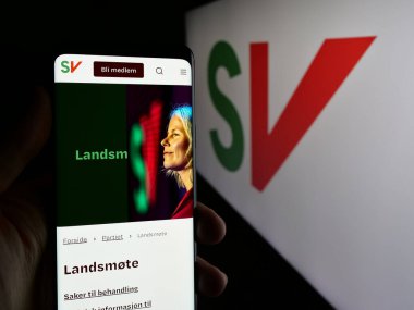 Stuttgart, Almanya - 07-24-2025: Sosialistisk Venstreparti 'nin (SV) web sayfası logonun önünde duran kişi. Telefon ekranının merkezine odaklan.