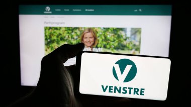 Stuttgart, Almanya - 07-24-2025: Norveç siyasi partisi Venstre 'nin logosunu web sayfasının önünde tutan kişi. Telefon ekranına odaklan.