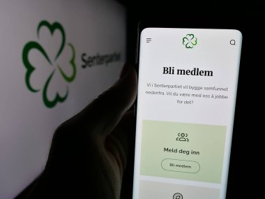 Stuttgart, Almanya - 07-24-2025: Norveç siyasi partisi Senterpartiet 'in (Sp) web sayfası logonun önünde duran kişi. Telefon ekranının merkezine odaklan.