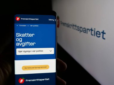 Stuttgart, Almanya - 07-24-2025: Norveç partisi Fremskrittspartiet 'in (FrP) web sayfası logonun önünde duran kişi. Telefon ekranının merkezine odaklan.