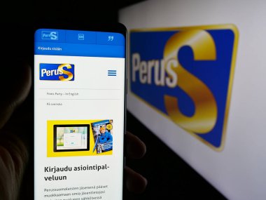 Stuttgart, Almanya - 07-25-2025: Fin partisi Perussuomalaiset 'in (PerusS) internet sayfası logonun önünde bulunan kişi. Telefon ekranının merkezine odaklan.