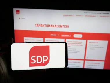 Stuttgart, Almanya - 07-25-2025: İnternet sitesinin önünde Suomen Sosialidemokratinen Puolue (SDP) logosuna sahip akıllı telefon sahibi kişi görülüyor. Telefon ekranına odaklan.