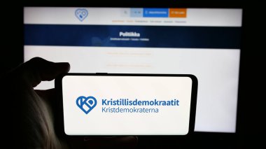 Stuttgart, Almanya - 07-25-2025: İnternet sayfası önünde Fin partisi Kristillisdemokraatit 'in (KD) logosunu elinde tutan kişi. Telefon ekranına odaklan.