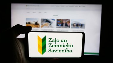 Stuttgart, Almanya - 07-28-2025: İnternet sayfası önünde Zalo un Zemnieku Savieniba (ZZZS) partisinin logosunu elinde tutan kişi. Telefon ekranına odaklan.