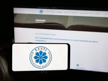 Stuttgart, Almanya - 07-28-2025: Web sitesinin önünde üzerinde Eesti Konservatiivne Rahvaerakond (EKRE) logosu bulunan kişi. Telefon ekranına odaklan.