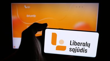 Stuttgart, Almanya - 07-28-2025: İnternet sayfasının önünde Lietuvos Respublikos Liberalu Sujudis (LRLS) logosu olan cep telefonu sahibi kişi. Telefon ekranına odaklan.