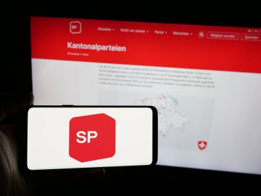 Stuttgart, Almanya - 07-28-2025: İnternet sitesinin önünde Sozialdemokratische Partei der Schweiz (SP) logosuna sahip akıllı telefon sahibi kişi. Telefon ekranına odaklan.