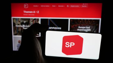 Stuttgart, Almanya - 07-28-2025: İnternet sayfasının önünde Sozialdemokratische Partei der Schweiz (SP) logosu olan cep telefonu sahibi kişi. Telefon ekranına odaklan.
