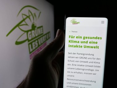 Stuttgart, Almanya - 07-30-2025: İsviçreli yeşil siyasi parti GRUENE Schweiz 'in web sayfasını elinde tutan kişi logonun önünde ekranda. Telefon ekranının merkezine odaklan.