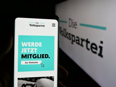 Stuttgart, Almanya - 07-30-2025: Osterreichische Volkspartei (OVP) partisinin web sayfası logonun önünde duran kişi. Telefon ekranının merkezine odaklan.