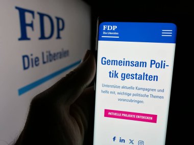 Stuttgart, Almanya - 07-30-2025: İsviçreli siyasi parti FDP Die Liberalen 'in internet sayfasını elinde tutan kişi logonun önünde ekranda. Telefon ekranının merkezine odaklan.