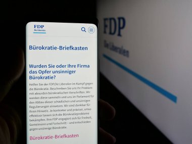 Stuttgart, Almanya - 07-30-2025: İsviçreli siyasi parti FDP Die Liberalen 'in internet sayfasını elinde tutan kişi logo önünde ekranda görülüyor. Telefon ekranının merkezine odaklan.