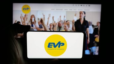 Stuttgart, Almanya - 07-30-2025: Web sayfası önünde Evangelische Volkspartei der Schweiz (EVP) logosunun bulunduğu cep telefonu sahibi kişi. Telefon ekranına odaklan.