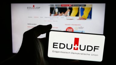 Stuttgart, Almanya - 07-30-2025: İnternet sayfası önünde Eidgenoessisch-Demokratische Union (EDU) partisinin logosunun bulunduğu cep telefonu sahibi kişi. Telefon ekranına odaklan.
