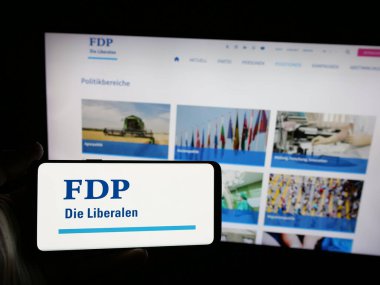 Stuttgart, Almanya - 07-30-2025: İsviçreli siyasi parti FDP Die Liberalen 'in logosunu elinde tutan kişi web sitesinin önünde ekranda. Telefon ekranına odaklan.
