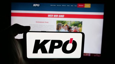 Stuttgart, Almanya - 08-01-2025: İnternet sayfası önünde üzerinde parti Kommunistische Partei Oesterreichs (KPO) logosu bulunan kişi. Telefon ekranına odaklan.