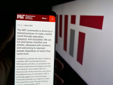 Stuttgart, Almanya - 08-01-2025: Logo önünde ekranda Massachusetts Teknoloji Enstitüsü (MIT) web sayfası bulunan kişi. Telefon ekranının merkezine odaklan.
