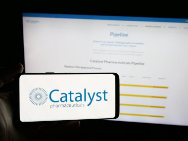 Stuttgart, Almanya - 08-07-2025: ABD 'li Katalizör İlaç Şirketi' nin logosunu elinde tutan kişi web sitesinin önünde ekranda. Telefon ekranına odaklan.